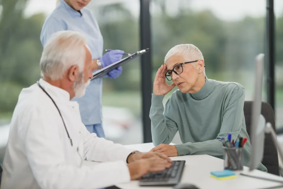 A family doctor talks with an older patient at a desk
